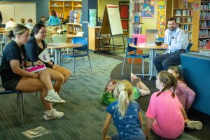 seniors read their books to fourth graders in the library