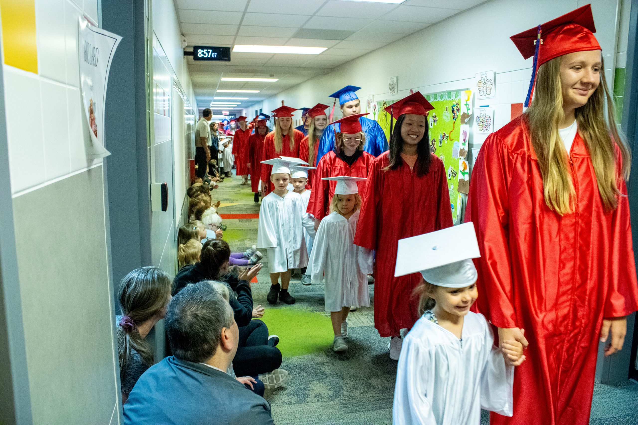 PK4 students walk with Seniors in caps and gowns
