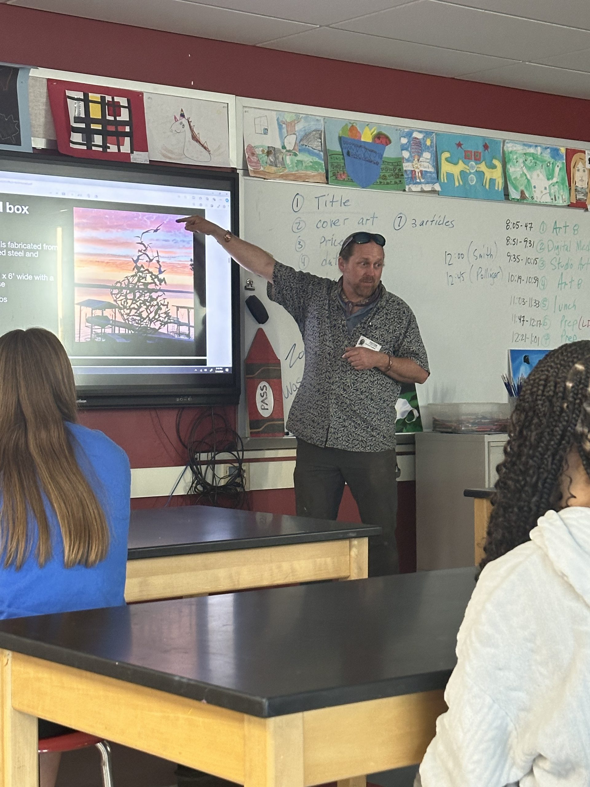 Man showing metal sculpture to art students in class